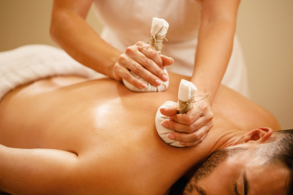 Therapist performing traditional Ayurvedic detox massage using herbal compress balls during Panchakarma treatment in Kolkata.