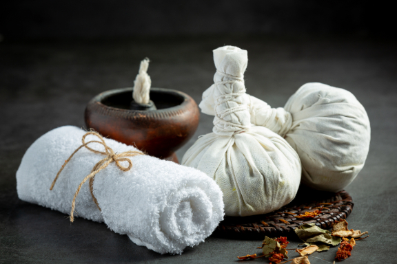 Herbal compress balls, towel, and Ayurvedic oil lamp arranged for traditional Panchakarma treatment in Kolkata.