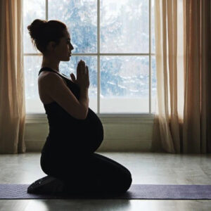 a pregnant lady is in prayer position that she learnt from pregnancy yoga classes in tollygunge